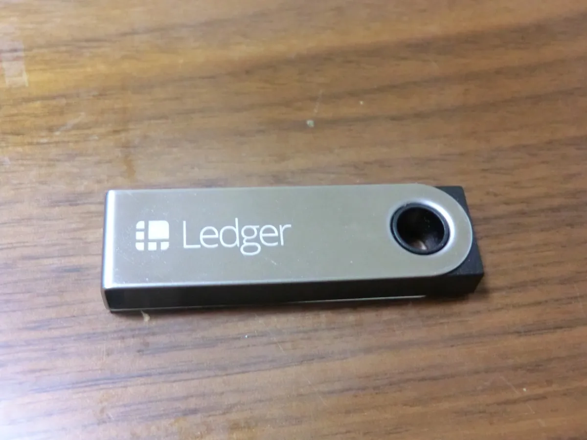 Un portefeuille matériel Ledger Nano S posé sur une table en bois